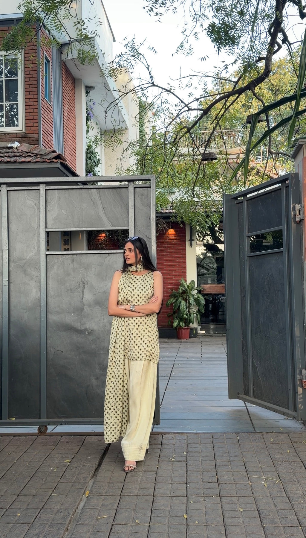 Woman in a light-colored dress standing in front of a modern house entrance.