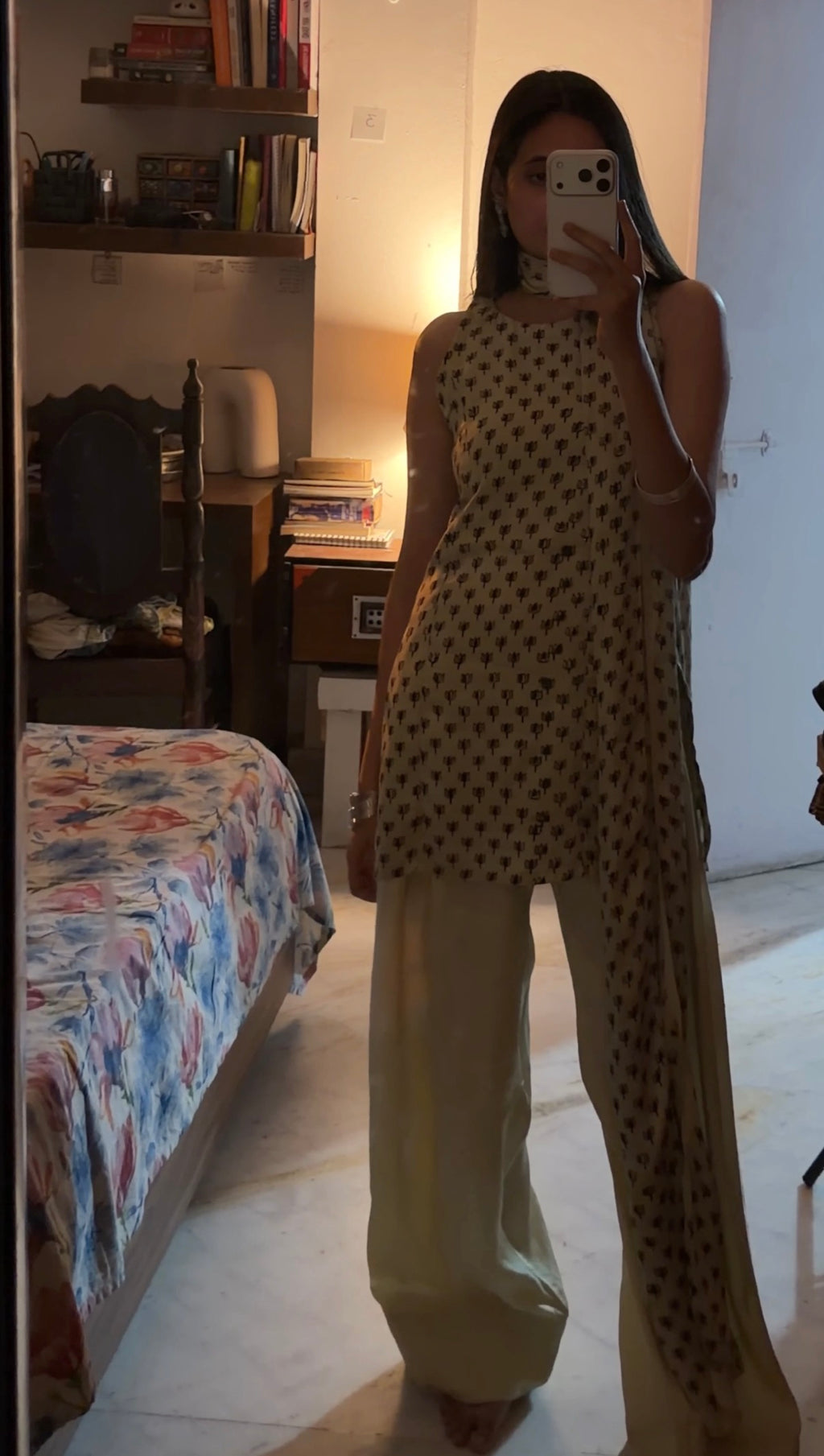 Person taking a mirror selfie wearing a patterned outfit in a bedroom.