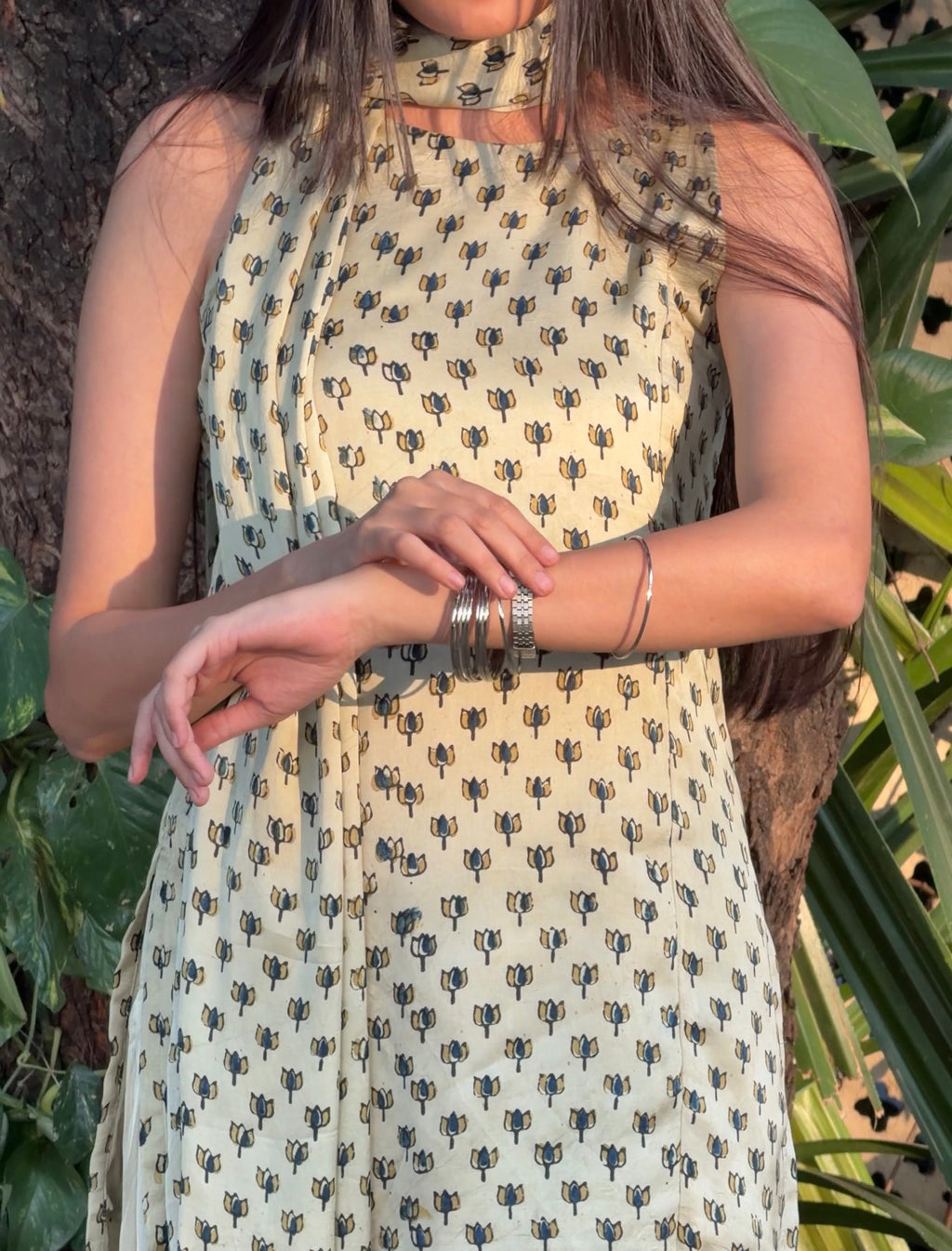 Person wearing a patterned dress with cactus design, standing among green plants.