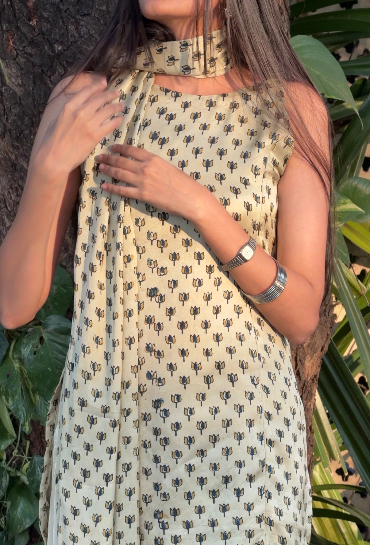 Woman wearing a patterned dress with greenery in the background